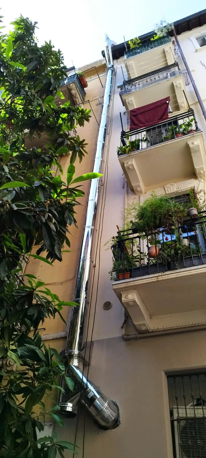 Canna fumaria in acciaio inox lungo la facciata interna di un palazzo d'epoca a Milano
