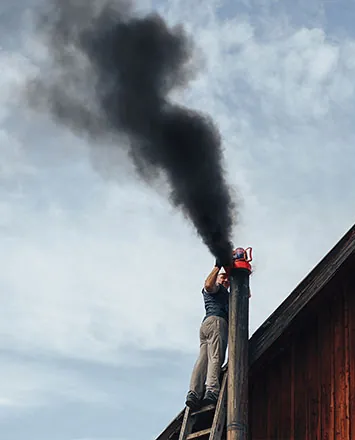 Fumo nero che esce da una canna fumaria durante la pulizia